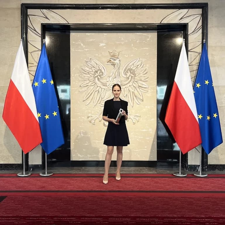 Nadia Sajjad z Nagrodą Ministra Rozwoju i Technologii, na tle godła Polski i flag